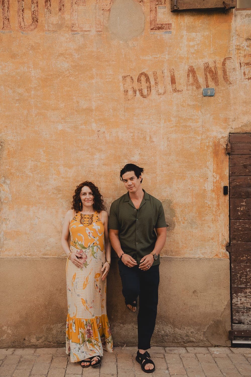 Couple adossé à un mur ocre dans une rue de Cassis lors d’une séance photo en extérieur