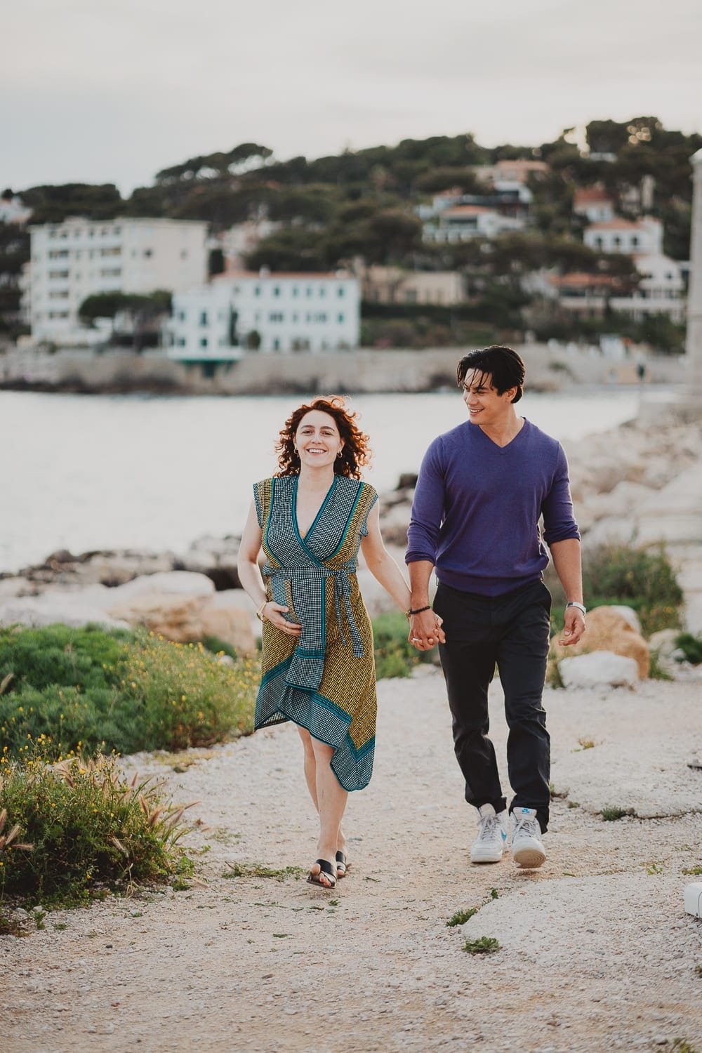 Couple marchant en bord de mer à Cassis lors d’une séance engagement au coucher du soleil.